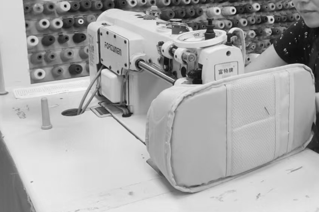 A woman sewing a compartment of a bag together