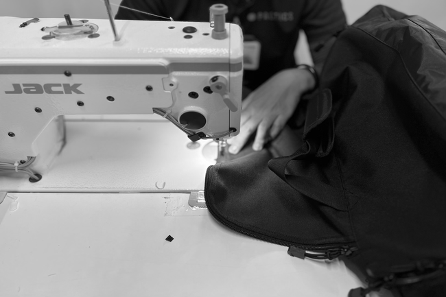 A woman stitching a bag