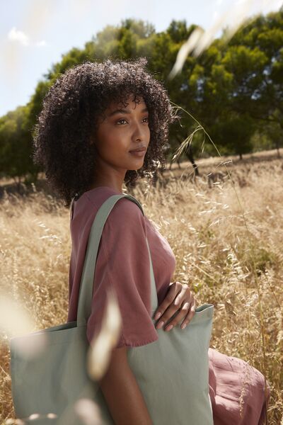Woman with Green Shopper Bag in a field