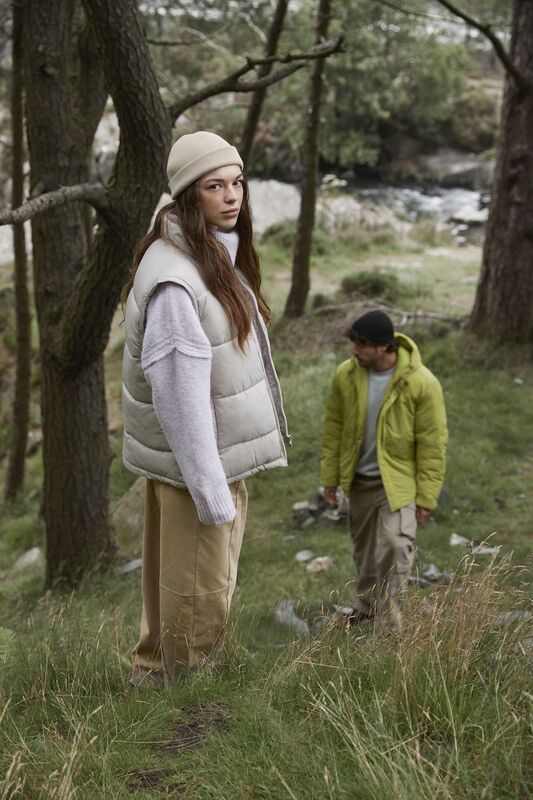 A man and woman wearing beanies standing in the forest
